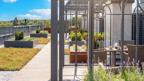 A rooftop garden with a wooden pathway, outdoor seating, and a decorative metal gate. - Modern Apartment with Air Conditioning | Roof Terrace (Ciechocinek)