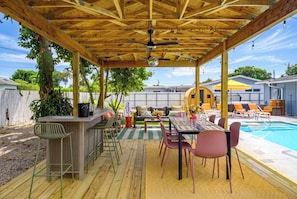 Ein Außenbereich mit Pool, Holzterrasse, Bar und Sitzgelegenheiten.