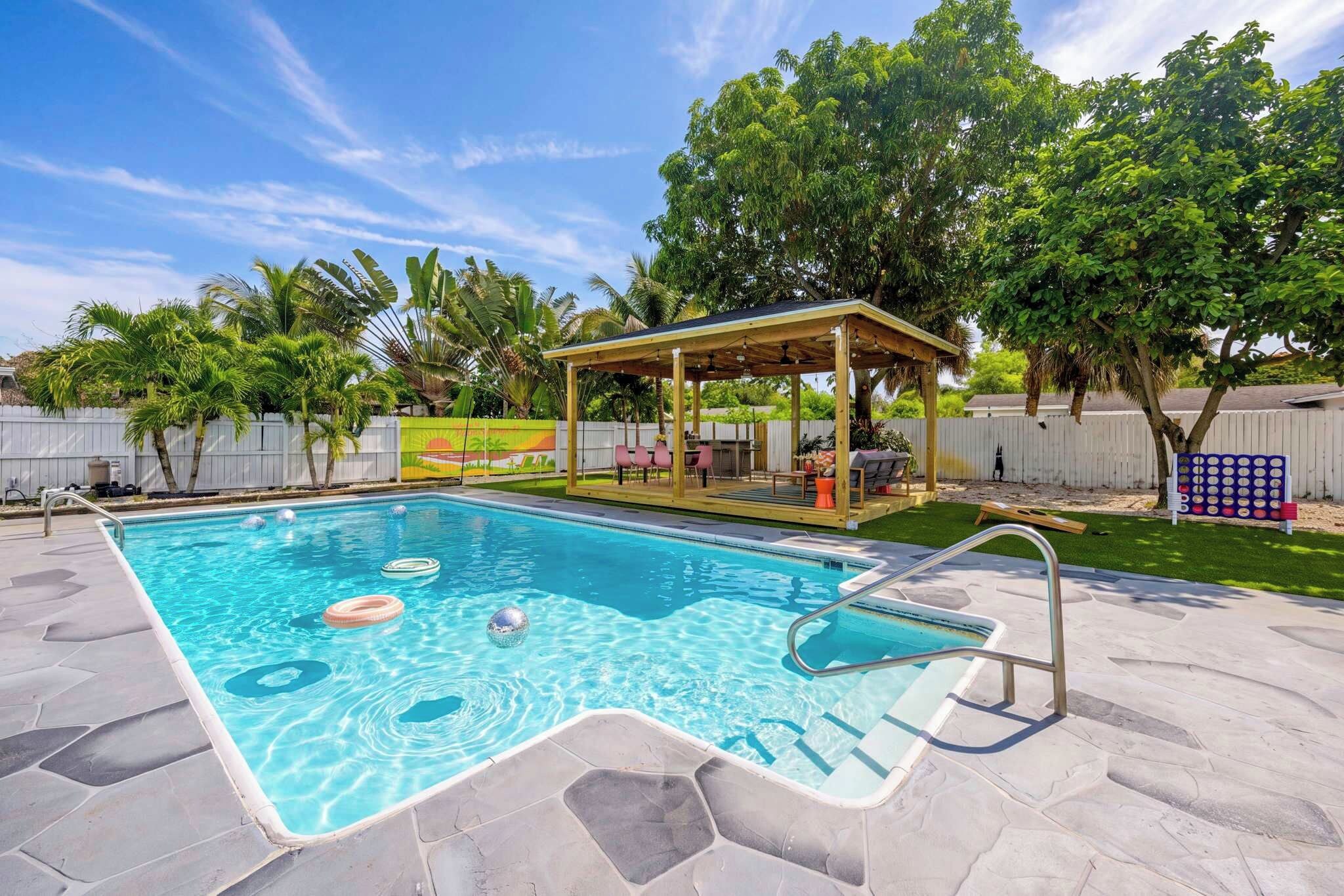 A swimming pool with a wooden deck and a covered seating area.