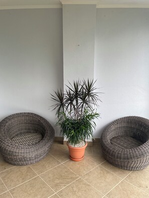 A room with two wicker chairs, a potted plant, and a tiled floor. - Luxury Oceanfront 2-bedroom condo in enchanting Jacó on the Beach!!! (Jacó)