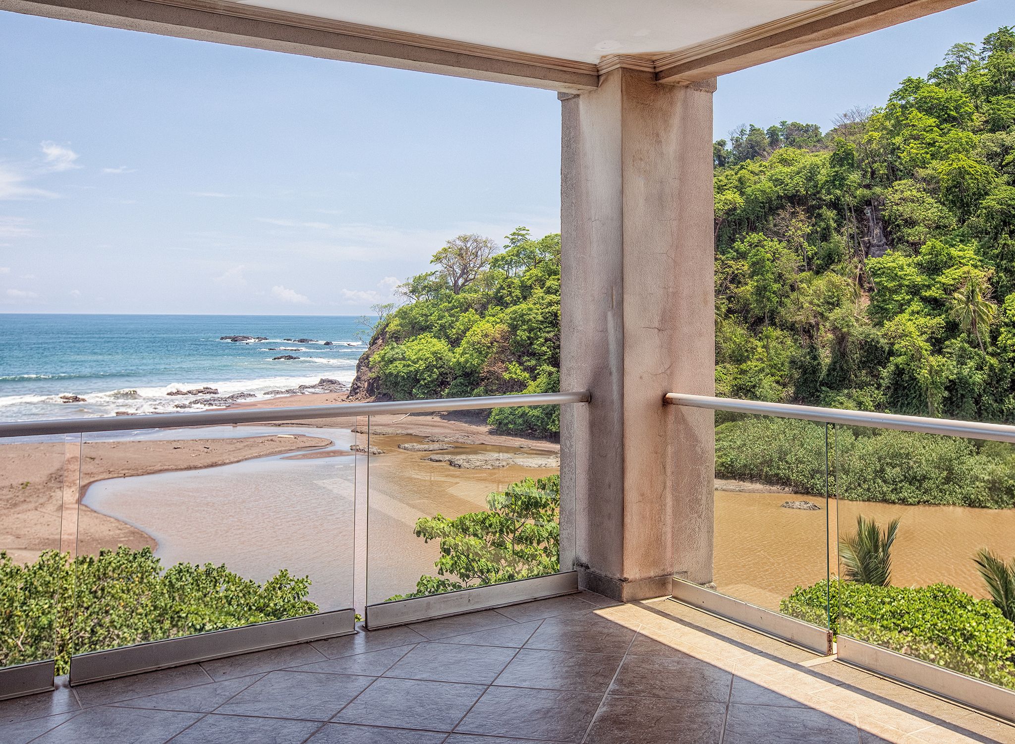 A balcony with a view of a beach and a river.