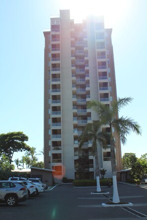 A high-rise building with multiple balconies, a parking lot, and palm trees. - Luxury Oceanfront 2-bedroom condo in enchanting Jacó on the Beach!!! (Jacó)