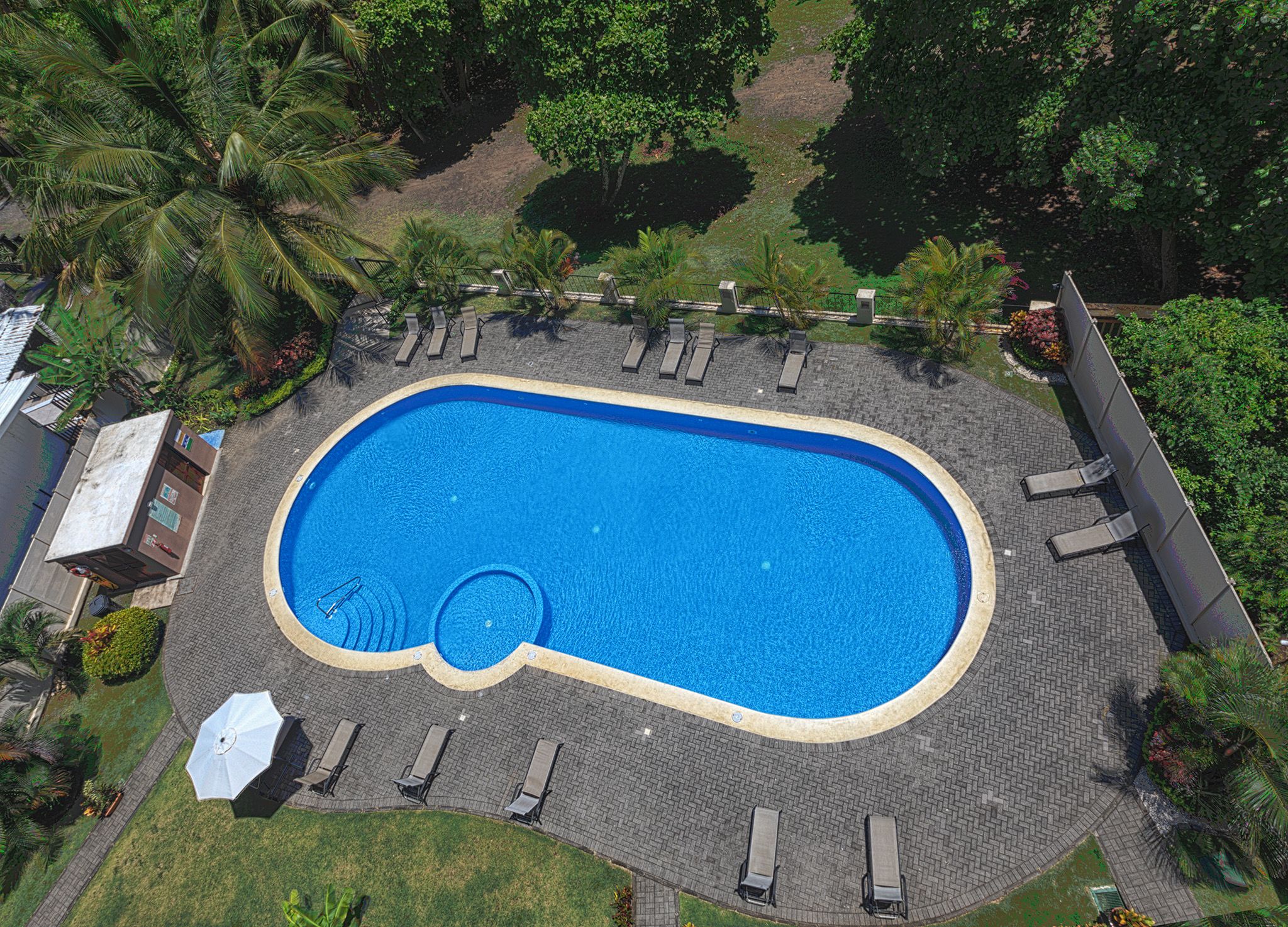 Eine Vogelperspektive auf einen Pool mit Liegestühlen und einer kleinen Liegefläche.