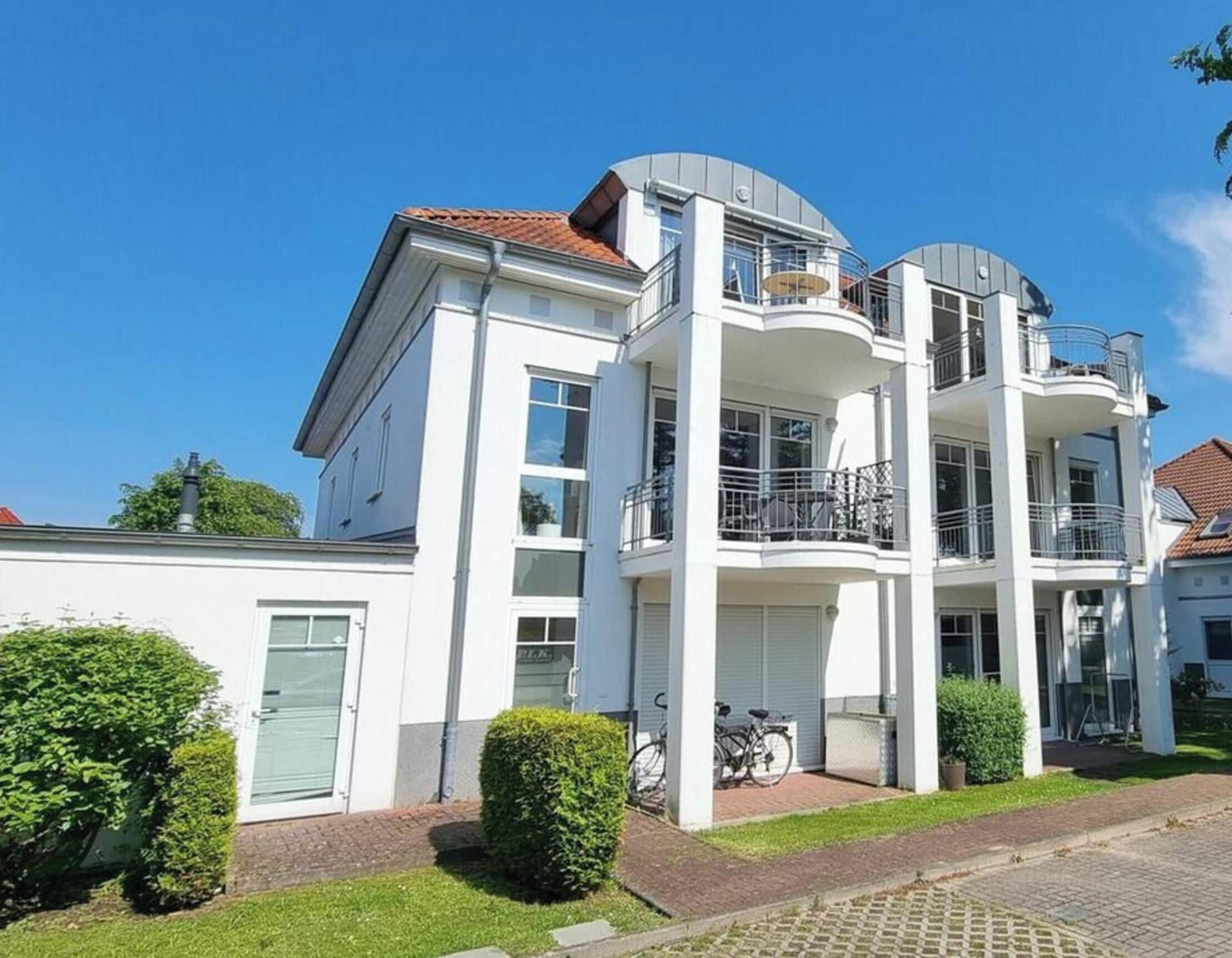 A multi-story residential building with a flat roof, balconies, and a garage.