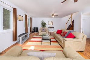 Ein Wohnzimmer mit einer Couch, einem Couchtisch, einer TV-Konsole und einer Treppe.
