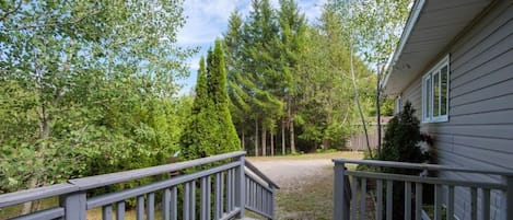 A wooden deck leading to a house surrounded by trees.