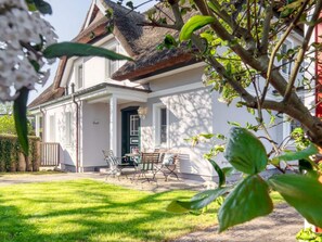 A house with a porch, outdoor seating, and a well-maintained lawn. - House Kranich-kate (Zingst)