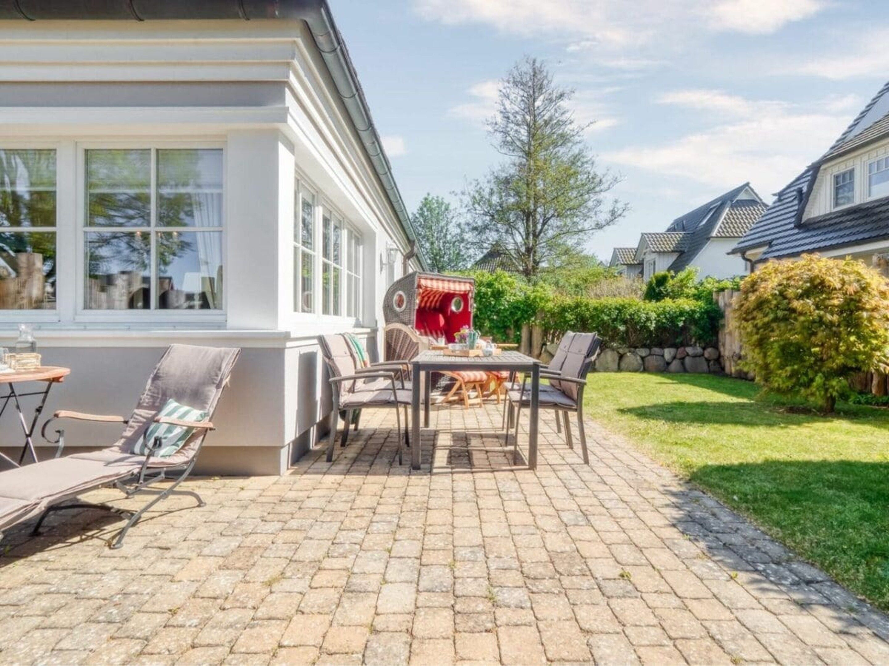 Eine Terrasse mit Gartenmöbeln, einem Tisch und Stühlen.