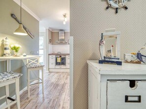 A kitchen with a stove, oven, and a hanging light fixture. - House Kranich-kate (Zingst)