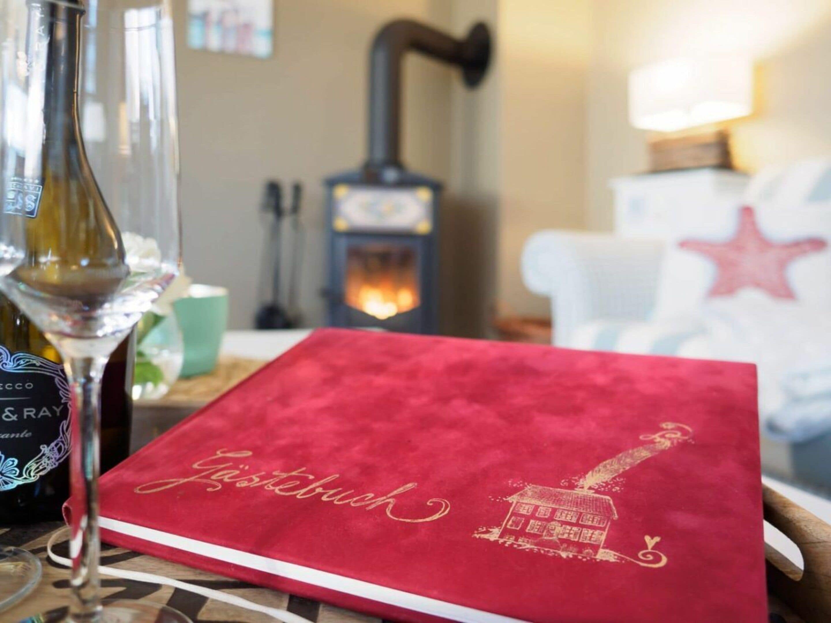 A red book titled 'Jästerbuch' on a table with a wine bottle and glasses.