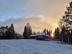 A snow-covered landscape with a house and a barn.