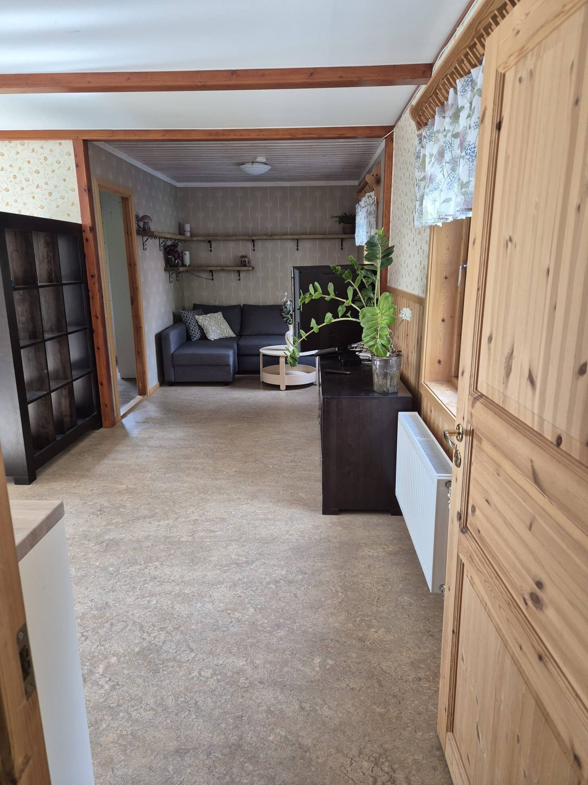 Una habitación con sofá, televisión, radiador y un mueble de madera.
