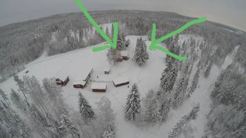 A snow-covered landscape with a cluster of buildings surrounded by dense forest.