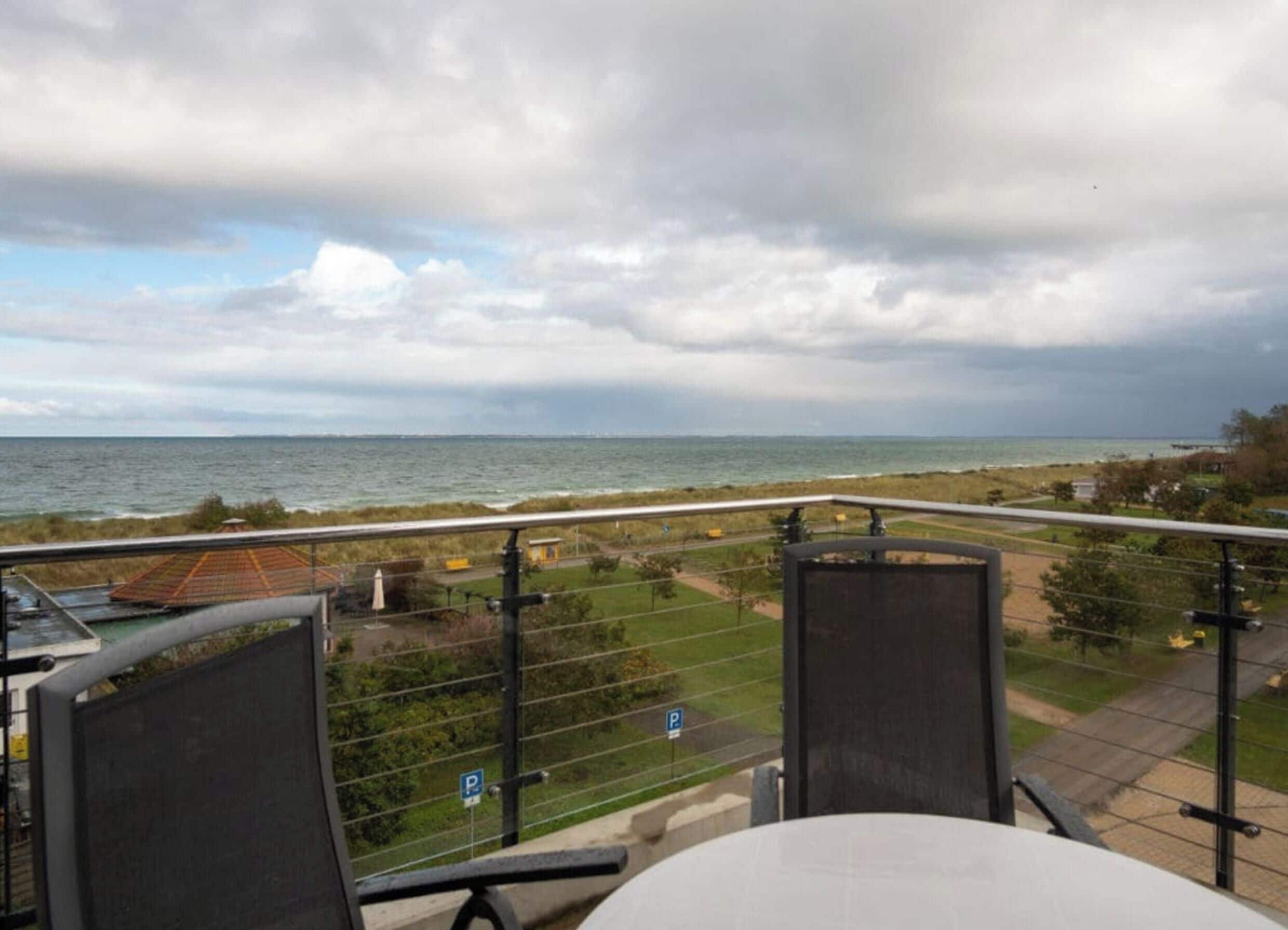 En balkong med utsikt över havet och en parkeringsplats.