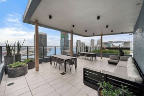 Eine Dachterrasse mit Essbereich, Sitzgelegenheiten und Kübelpflanzen.