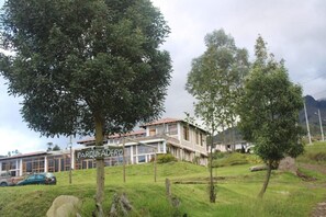 Un edificio con un letrero que dice 'PARQUEADOR', rodeado de árboles y césped.