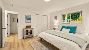 Et soveværelse med seng, et vindue med udsigt, en dør og et lille skab.