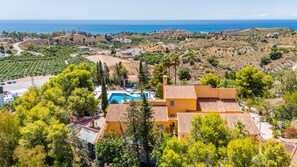 Eine Villa mit Swimmingpool, umgeben von üppiger Vegetation mit Blick auf eine Küstenlandschaft.
