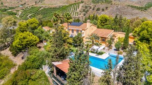 Une grande maison avec une piscine, entourée d’arbres.