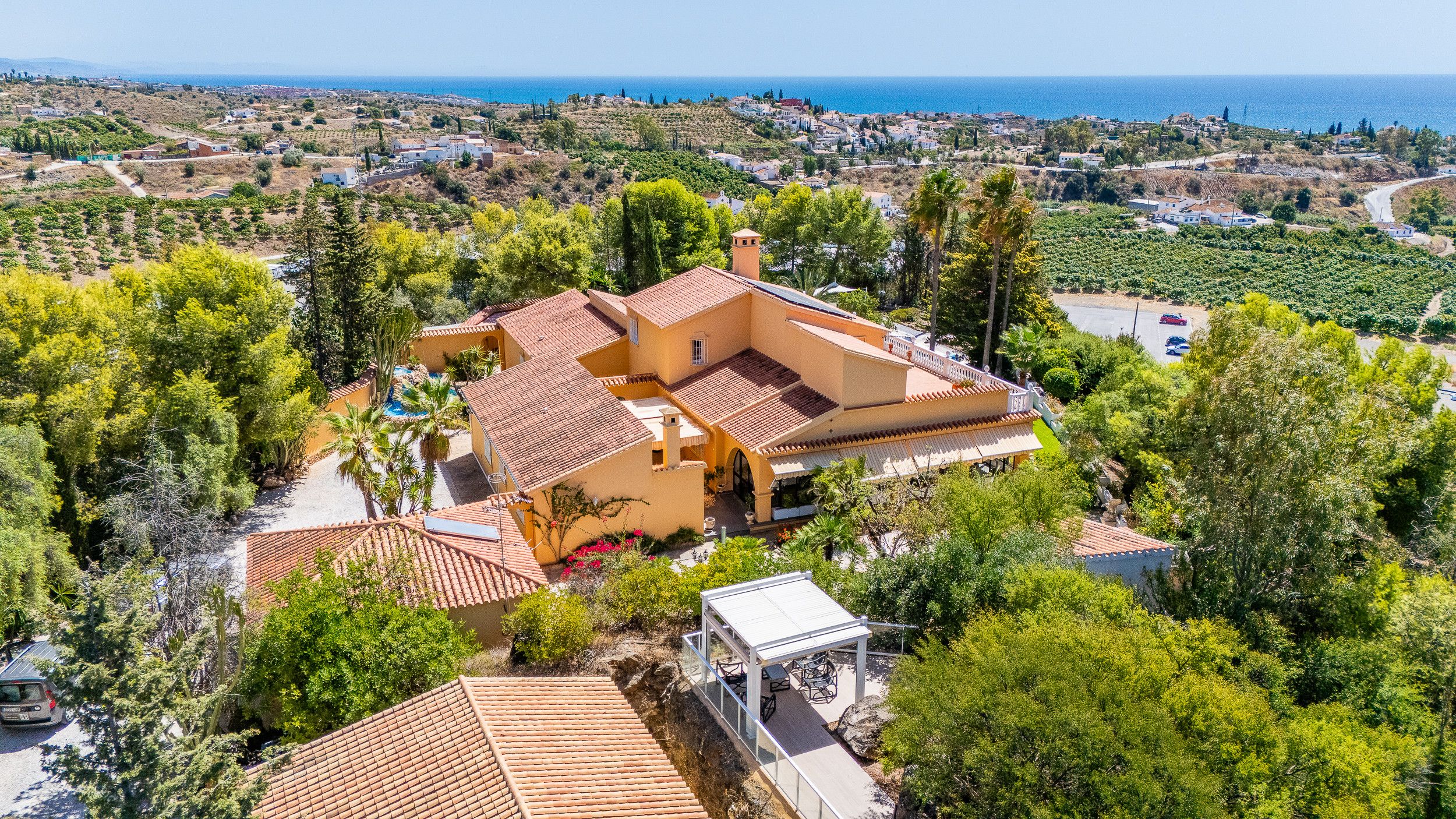 Una villa in stile mediterraneo con tetto in terracotta, circondata da vegetazione lussureggiante e affacciata su un paesaggio costiero.