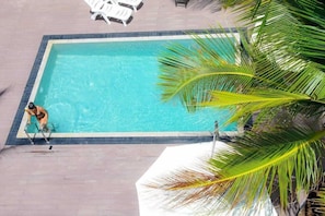 A rectangular swimming pool with clear water, surrounded by a tiled deck.