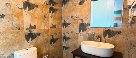 A bathroom with a toilet, a sink, and a mirror.