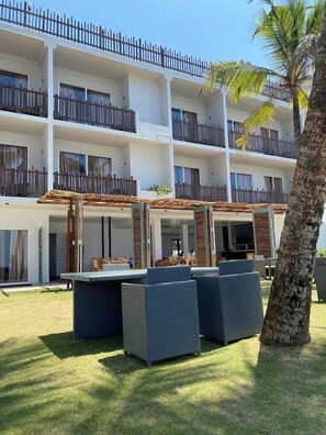 A multi-story hotel with outdoor seating and a palm tree.