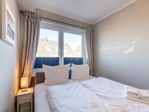 Habitación de hotel con una cama, una mesita de noche, una lámpara y una ventana con cortinas.