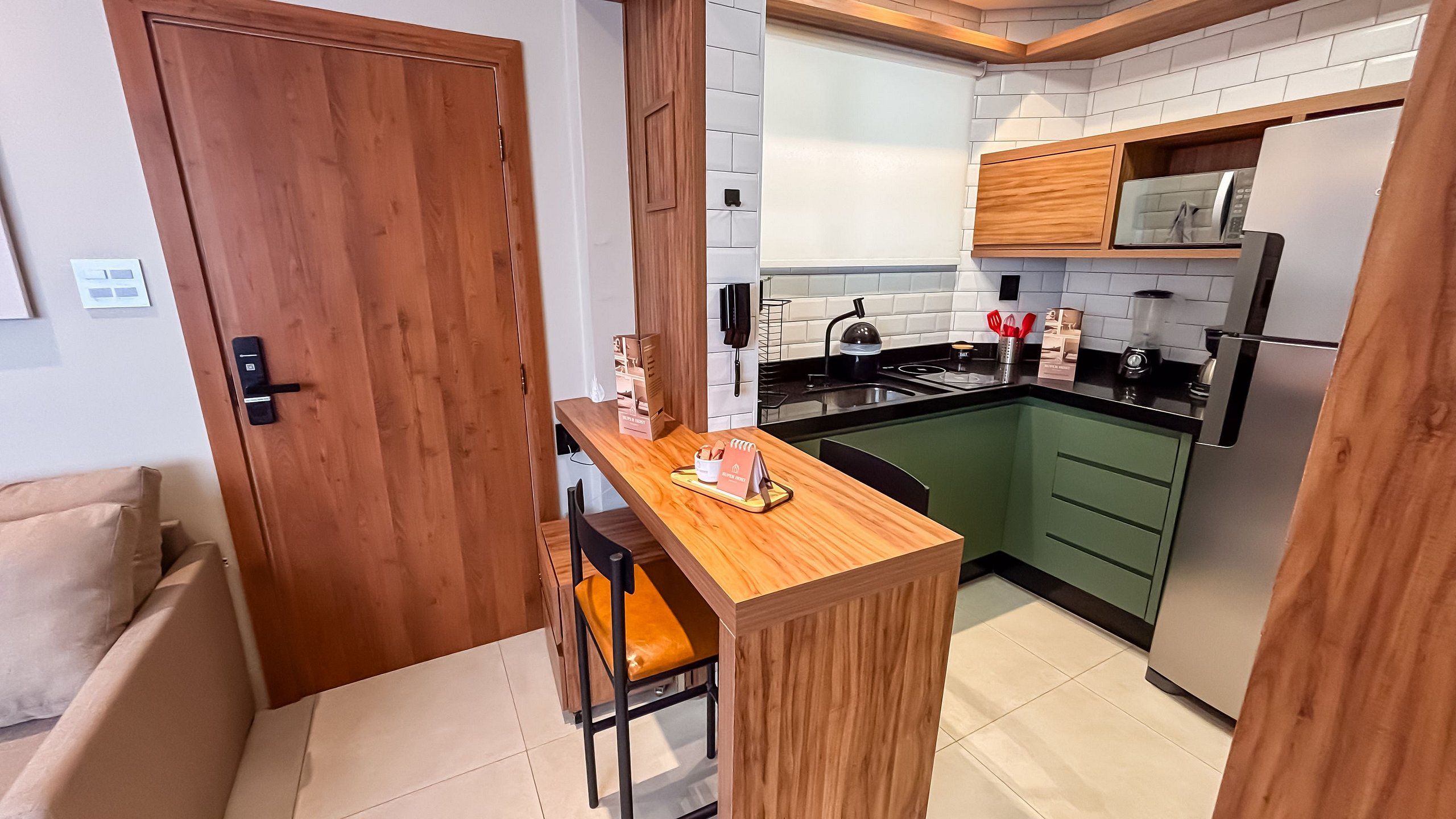 Una cocina compacta con una isla de madera, un microondas integrado y un refrigerador.