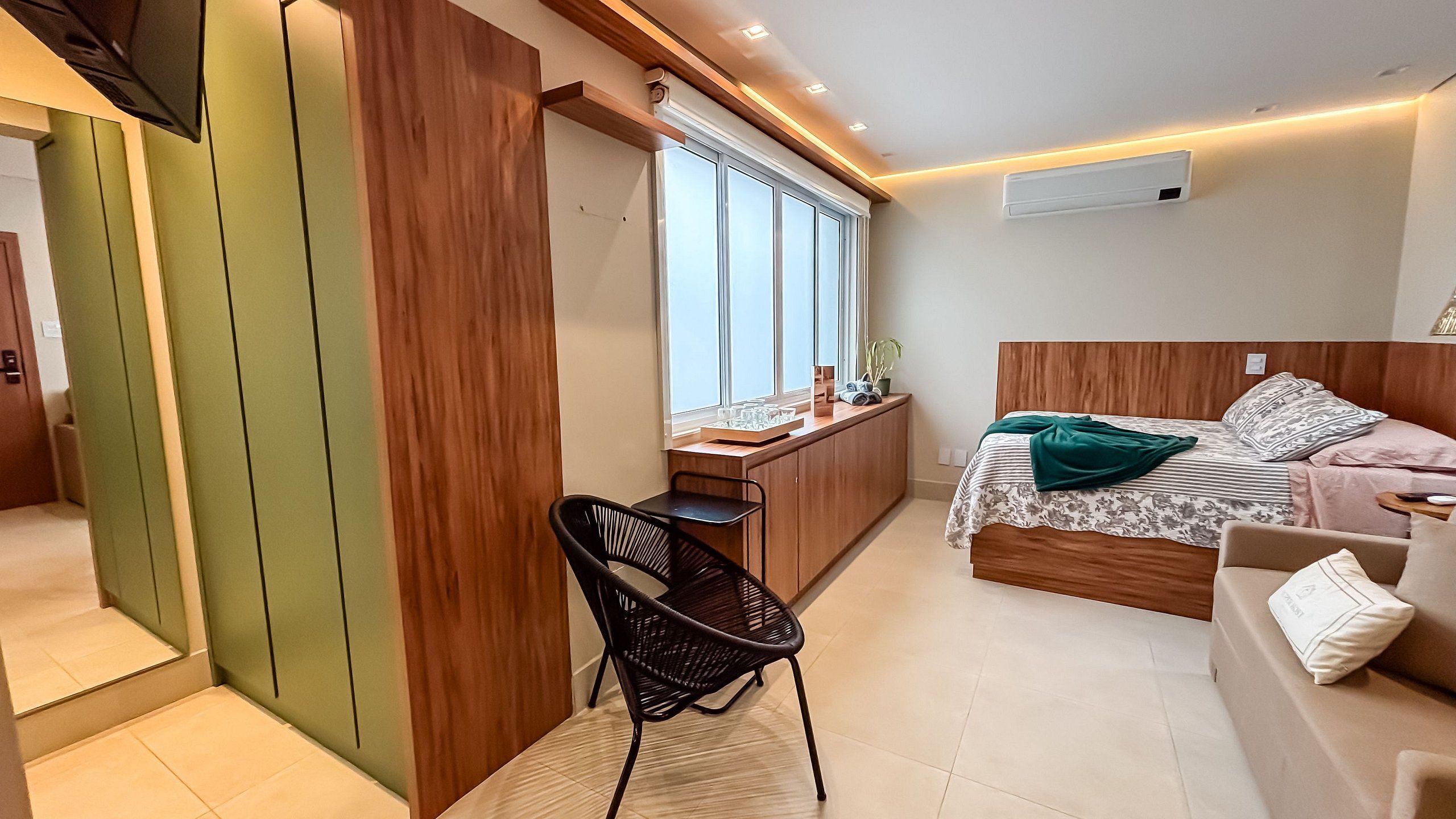 Un dormitorio pequeño con cama, un escritorio, una silla y una ventana.