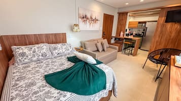 Una camera da letto moderna con un letto grande, un divano, un'area pranzo e una cucina.