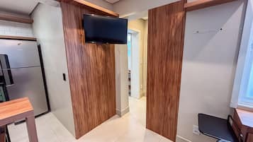 Una cocina moderna con refrigerador empotrado y un televisor de pantalla plana montado en una pared de madera.