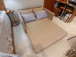 Ein Zimmer mit einem Bett, einem kleinen runden Tisch und einer Küchenzeile.