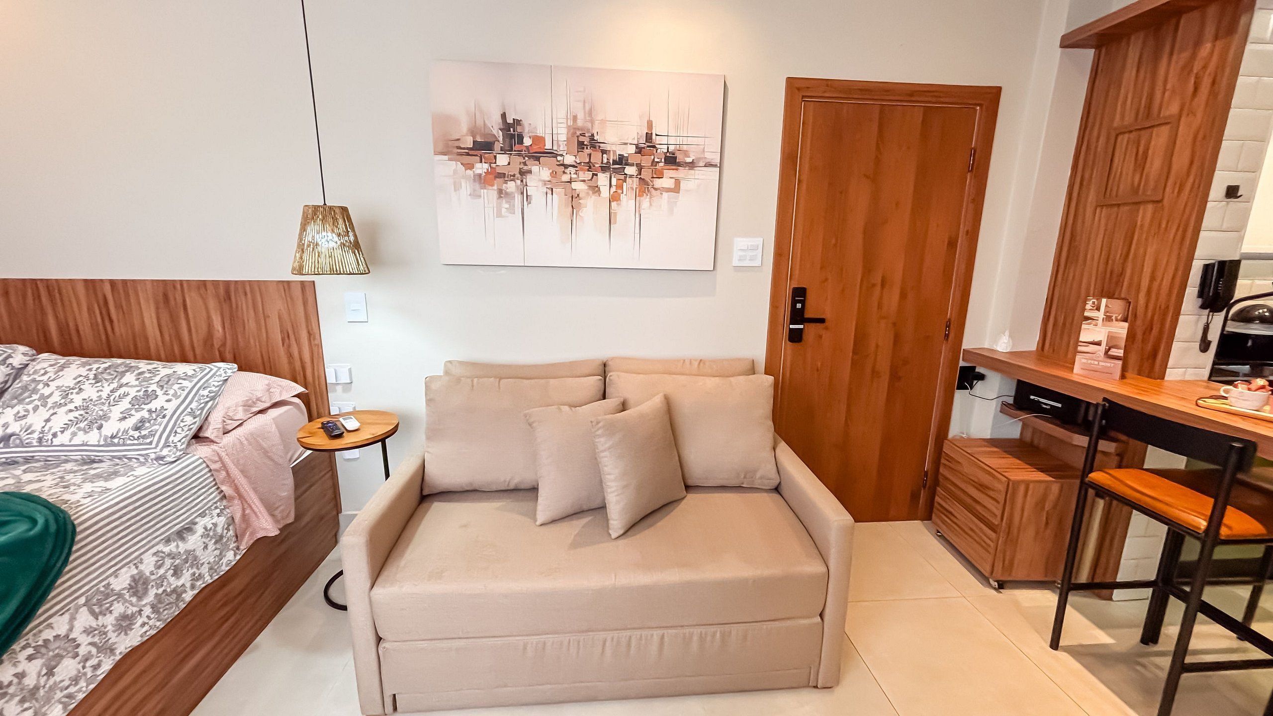 A bedroom with a bed, a sofa, a desk, and a door.