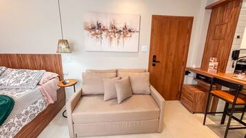 A bedroom with a bed, a sofa, a desk, and a door.