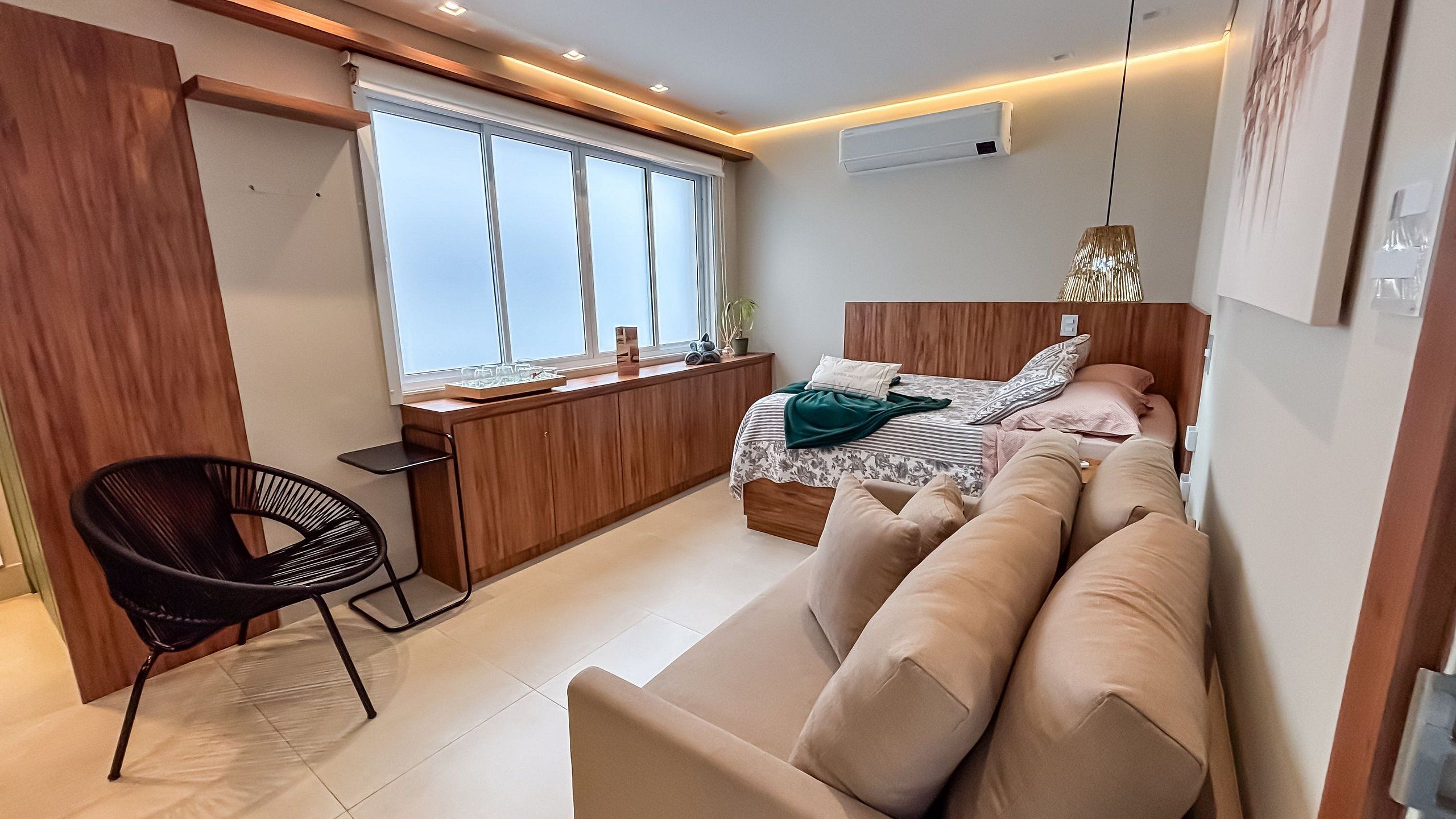 Una habitación funcional con cama, sofá, escritorio y silla.