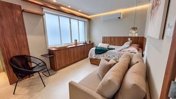 Una habitación funcional con cama, sofá, escritorio y silla.