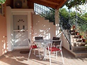 An outdoor patio with a table and chairs, a white door, and a staircase with potted plants. - Kuča na rjeci s velikim vrtom I pogledom na planinu, 3 km.od mora-Split 10km. (Žrnovnica)