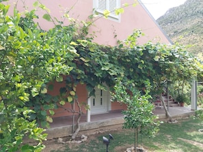 A house with a covered porch, a small tree, and a garden area. - Kuča na rjeci s velikim vrtom I pogledom na planinu, 3 km.od mora-Split 10km. (Žrnovnica)