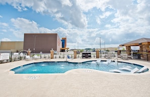 A swimming pool with a no diving sign, lounge chairs, and a building in the background. - Free Breakfast! 2BR Suite + Outdoor Pool Access (Humble)