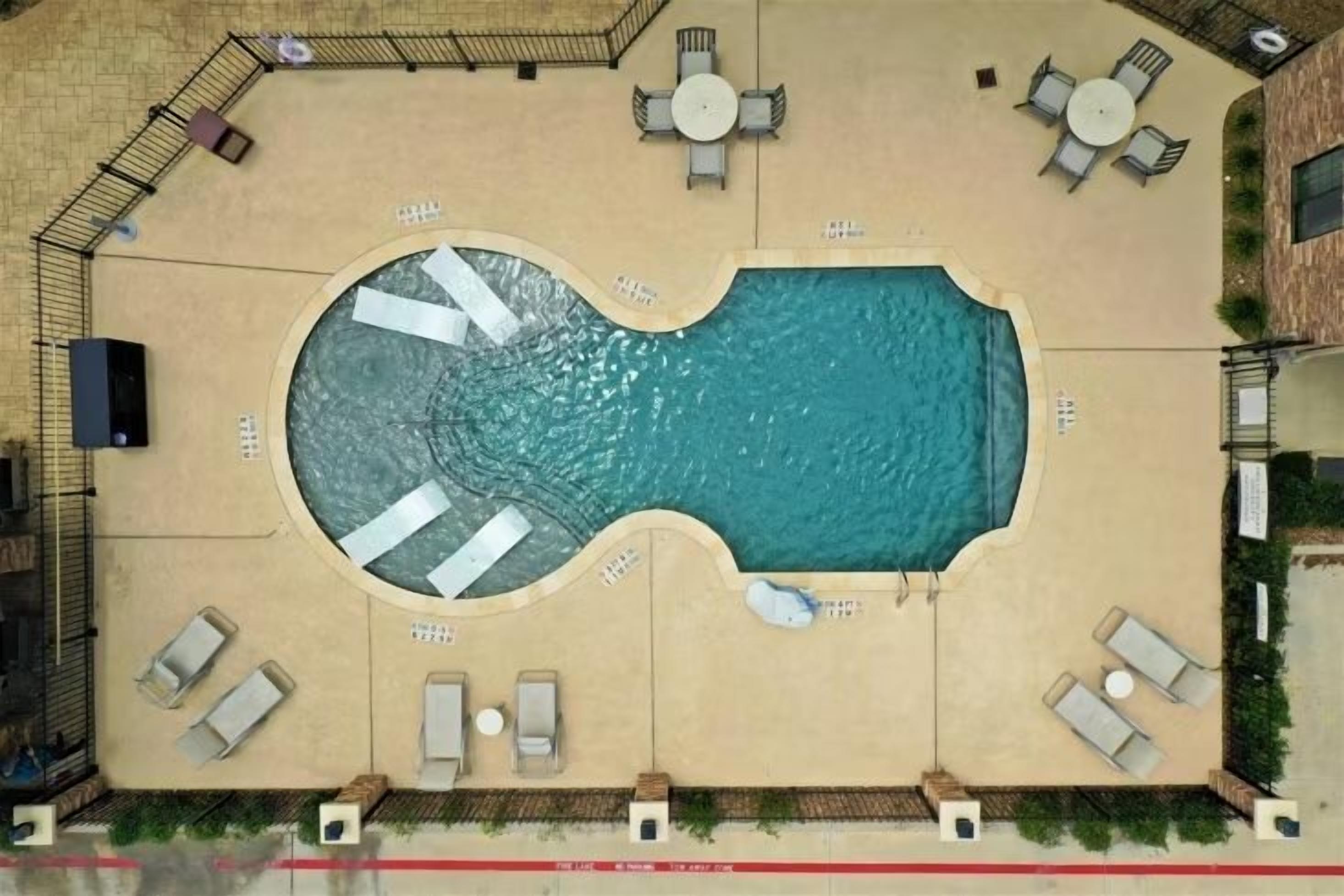 An aerial view of a swimming pool with sun loungers and a small deck area.