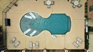 An aerial view of a swimming pool with sun loungers and a small deck area.