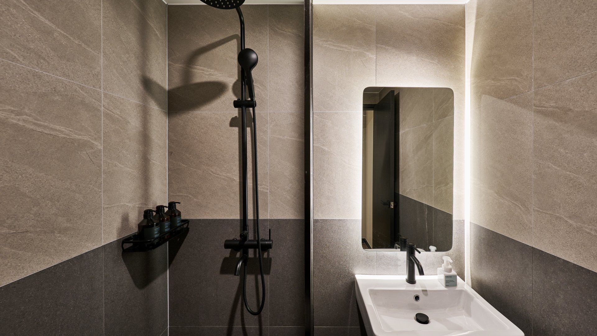 A modern bathroom with a shower, a sink, and a mirror.