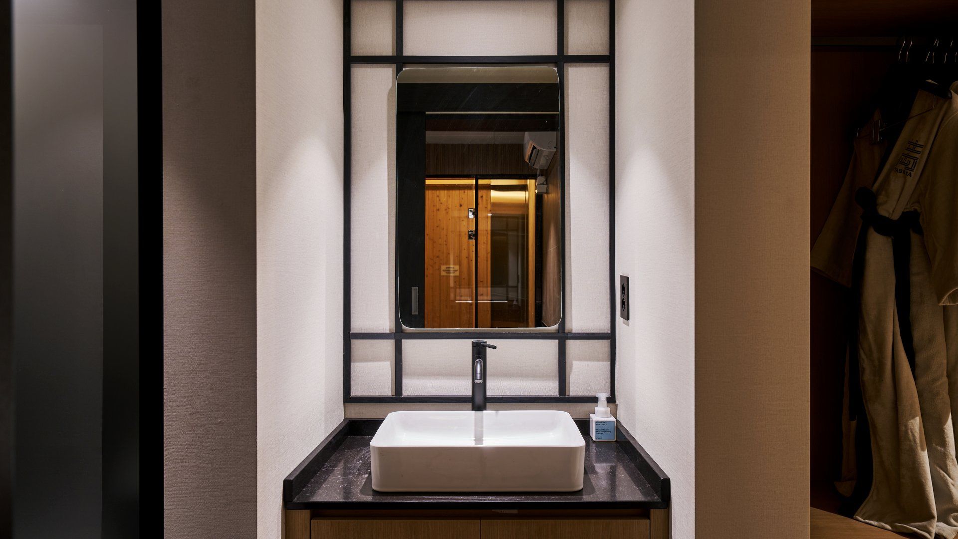 Une salle de bain avec un grand miroir, un lavabo et un porte-serviettes.