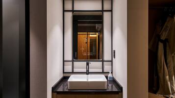 Une salle de bain avec un grand miroir, un lavabo et un porte-serviettes.