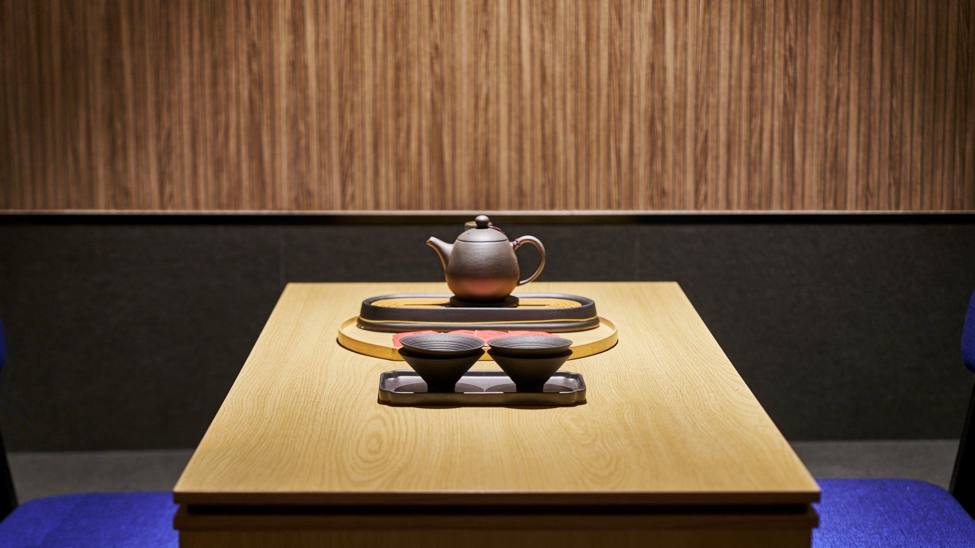 Una mesa de madera con un tetera y dos tazas sobre una bandeja.