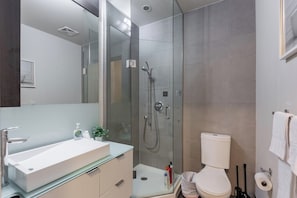 Ein modernes Badezimmer mit einer Duschkabine, einem weißen Waschbecken und einer Toilette.
