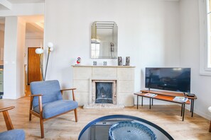 Un salon avec une cheminée, un téléviseur et un fauteuil bleu.