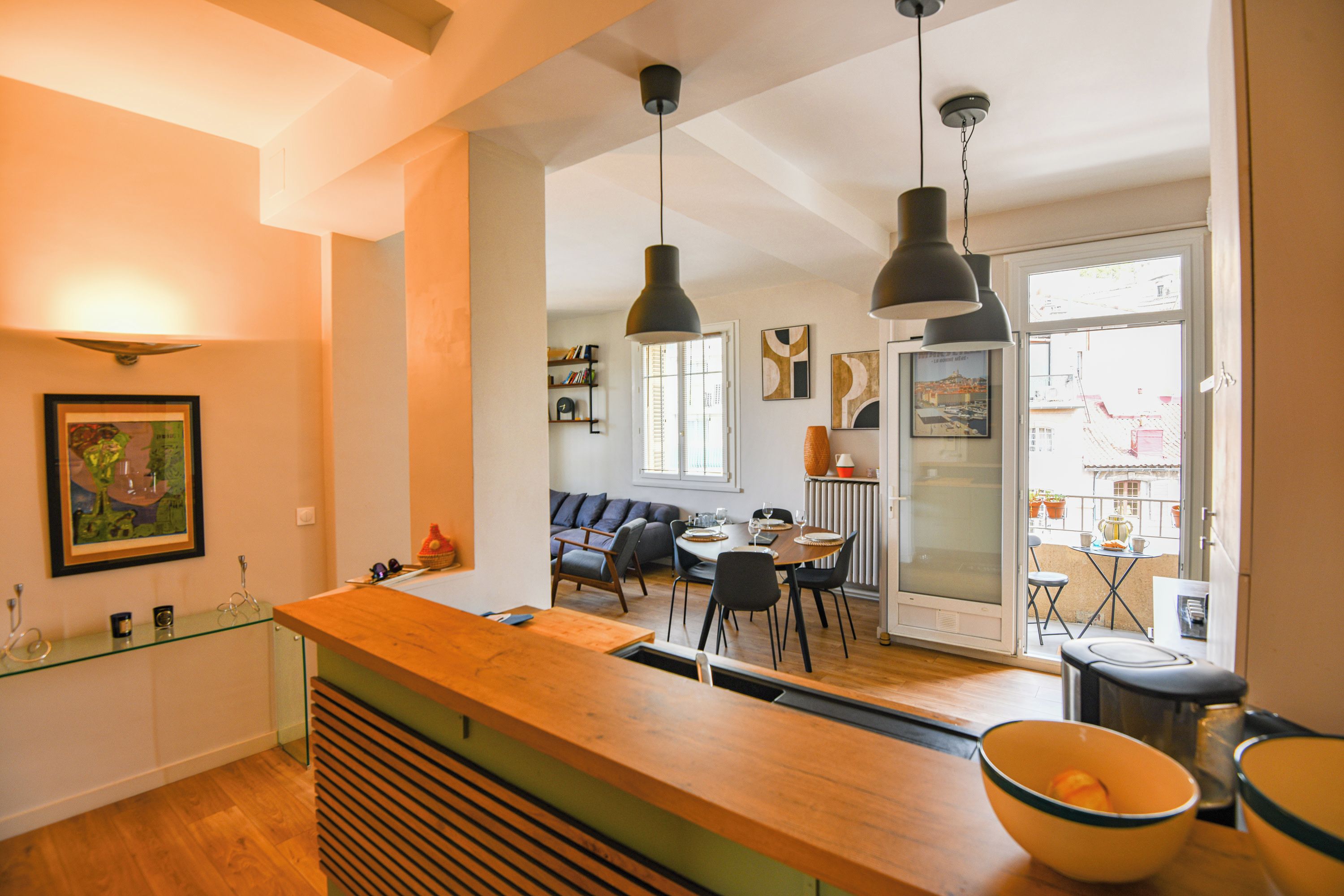 Een moderne keuken met een houten aanrecht, zwarte hanglampen en uitzicht op een eetgedeelte met een tafel en stoelen.