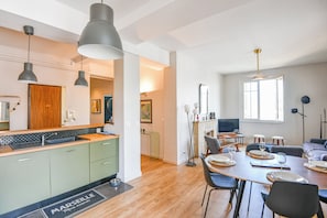 A modern kitchen with green cabinets, a wooden countertop, and pendant lighting. - Bail mobilité - Vue sur le Panier - Balcon - 2 ch (Marseille)